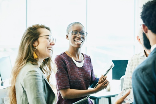 Smiling business colleagues in discussion during informal meeting in start up office