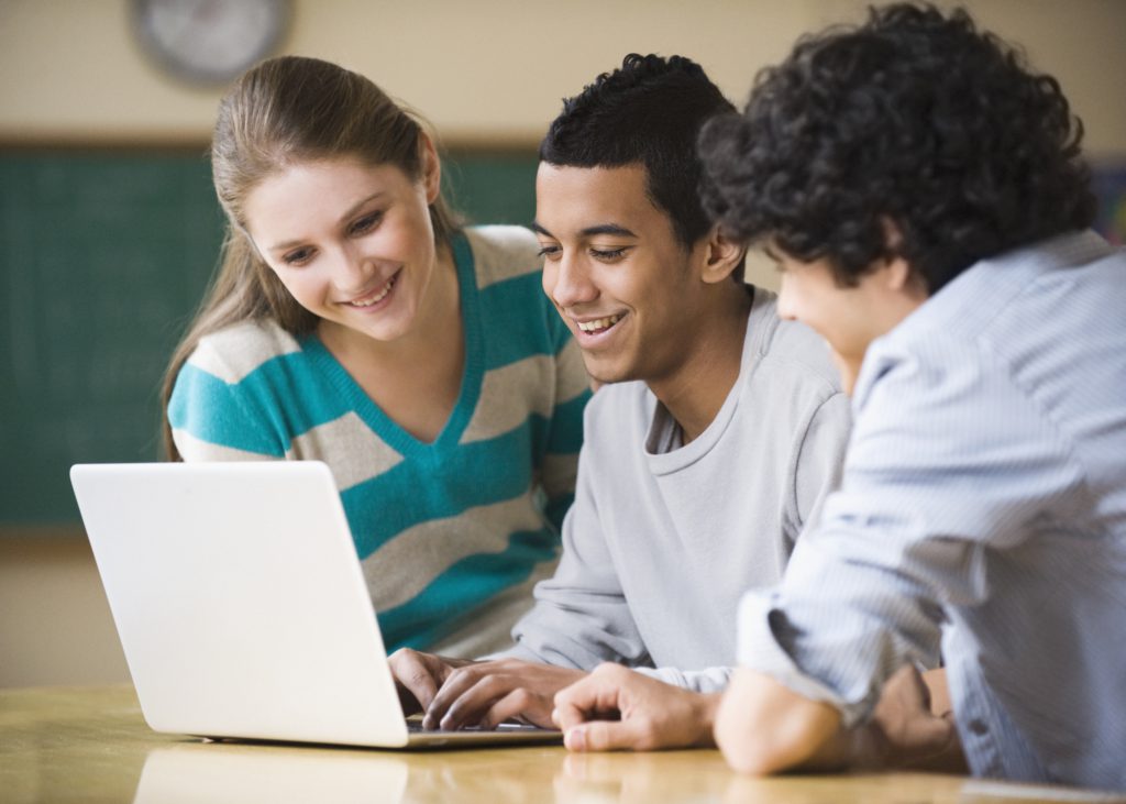 Diverse teens looking at laptop
